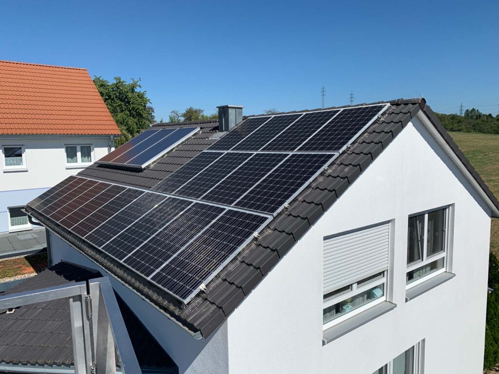 Sonnenkollektoren glänzen auf Hausdach.